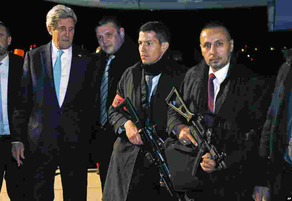 U.S. Secretary of State John Kerry looks over the weapons carried by Swiss police posing for a picture with him as he departs Geneva, Switzerland, Jan. 14, 2015.