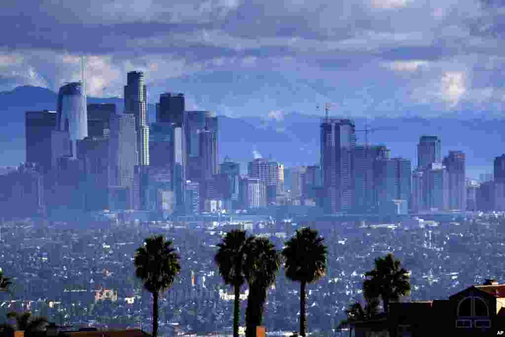 Heavy storm clouds and a dusting of snow are seen in the San Gabriel mountain range behind downtown Los Angeles.