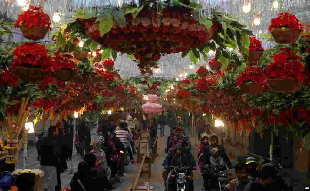 Motorcyclists drive through a street decorated with flowers on the eve of celebrations marking the birth of Islam&#39;s Prophet Muhammad, in Lahore, Pakistan.