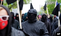 Black-clad protesters take part in a May Day march, May 1, 2015 in Seattle.