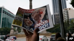 FILE - A street vendor hawks a newspaper emblazoned with an image of Donald Trump with a clown's nose and a headline that reads in Spanish: "We're screwed!" in Mexico City, Nov. 9, 2016.