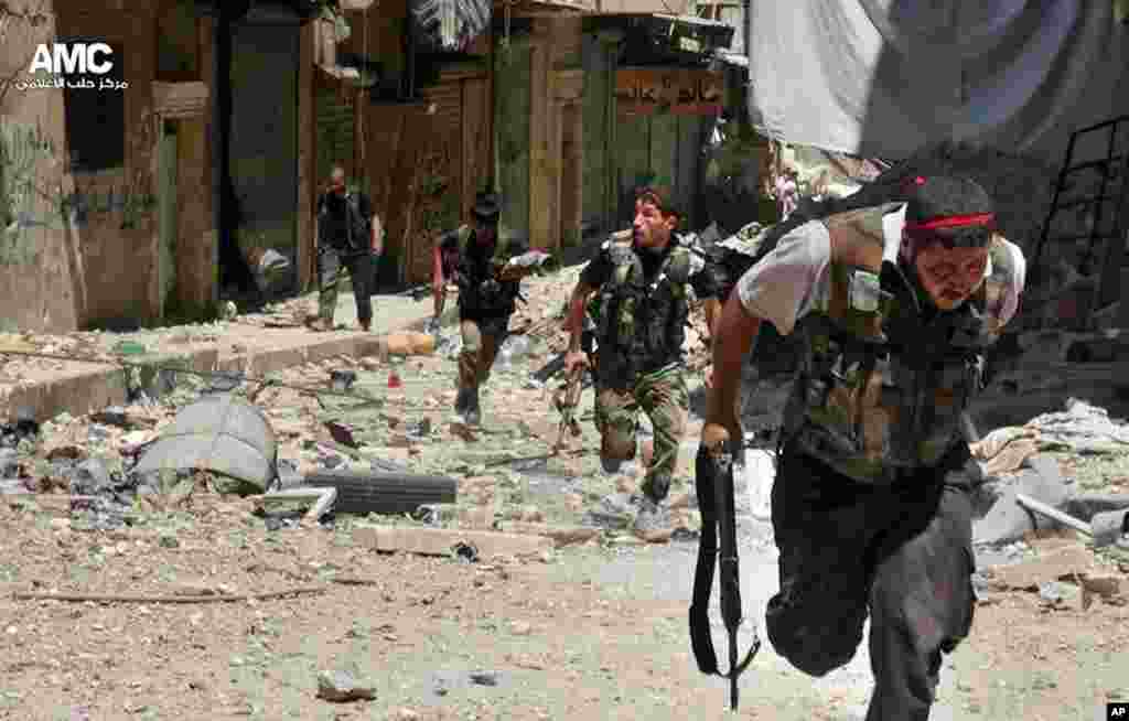 This citizen journalism image provided by Aleppo Media Center AMC shows Syrian rebels running during heavy clashes with Syrian soldiers in the Salah al-Din neighborhood of Aleppo, Syria, July 9, 2013.