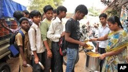 An Indian teacher serves the mid-day meal to children at a Government High School in Hyderabad, January 10, 2012. 