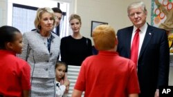 President Donald Trump, Education Secretary Betsy DeVos, his daughter Ivanka and Janayah Chatelier, 10 (L) listen to Landon Fritz, 10, during a tour of Saint Andrew Catholic School, March 3, 2017, in Orlando, Fla. 
