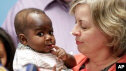 Foster mom Nancy Swabb holds Dominique, a 10-month-old baby born with two spines and an extra set of legs protruding from her neck during a news conference, March 21, 2017, at Advocate Children's Hospital in Park Ridge, Ill. (AP Photo/Teresa Crawford)