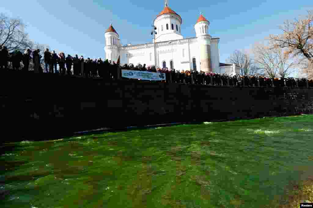 People look on, as the Vilnele River colors green during the St. Patrick&#39;s Day celebrations, at the Uzupis neighborhood in Vilnius, Lithuania, March 17, 2018.