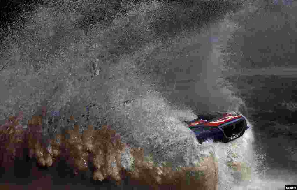 Sebastien Loeb of France drives his Peugeot through the water during the Buenos Aires-Rosario prologue stage of Dakar Rally 2016 in Arrecifes, Argentina, Jan. 2, 2016.