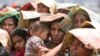 FILE - A Bangladeshi woman shields her baby from the sun as she stands in a line at a rice shop in Dhaka, April 5, 2008.