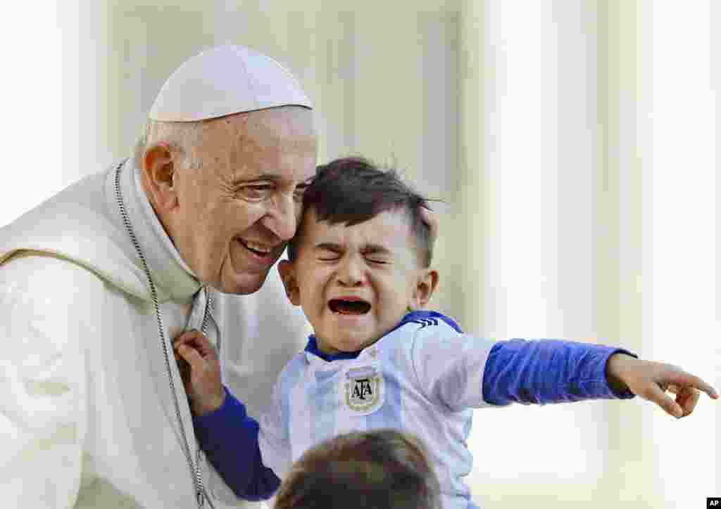 Pope Francis greets a child as he arrives on his popemobile in St.Peter's Square for his weekly general audience at the Vatican.