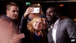 L'acteur Omar Sy (à dr.) pose pour des selfies avec des fans avant la première du film 'Inferno' à Berlin, lundi 10 octobre 2016. 