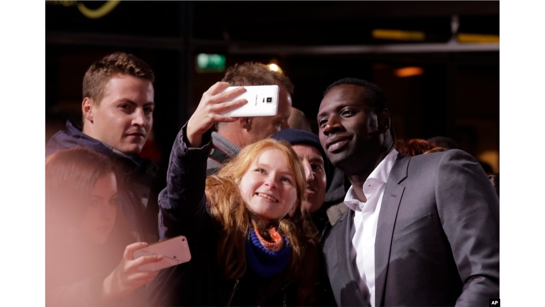 FILE - Actor Omar Sy poses for selfies with fans before the premiere of the movie "Inferno" in Berlin, Oct. 10, 2016.