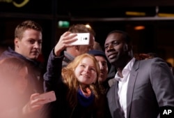FILE - Actor Omar Sy poses for selfies with fans before the premiere of the movie "Inferno" in Berlin, Oct. 10, 2016.
