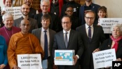 France's President Francois Hollande, center, holds a box containing an international petition to support the climate talks as he poses with religious figures for a group photo at the Elysee Palace in Paris, Dec. 10, 2015. 