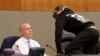 Stevante Clark jumps on the dais and shouts at Sacramento Mayor Darrell Steinberg, left, during a city council meeting in Sacramento, California, March 27, 2018. 