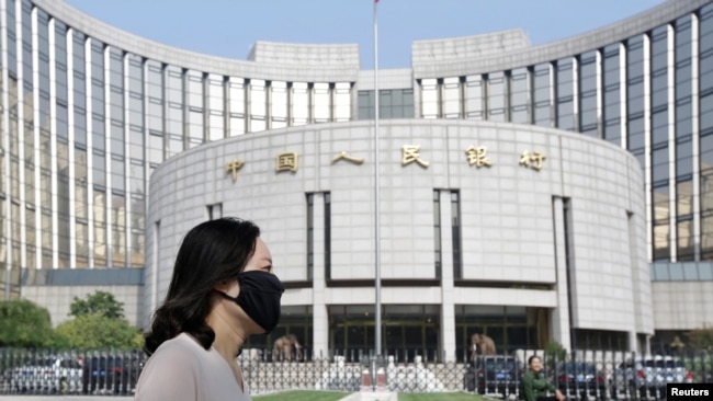 北京的中国人民银行总部大楼前，有人戴口罩走过（2018年9月28日）。
