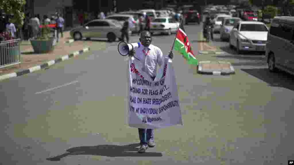 Un manifestant crie dans un mégaphone tout en tenant le drapeau du Kenya à l&#39;extérieur du bâtiment du Parlement à Nairobi, au Kenya jeudi 18 décembre 2014.