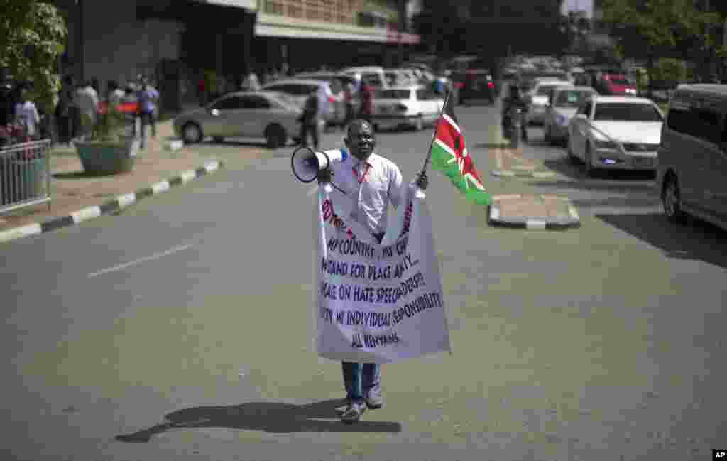 A protester shouts into a megaphone while holding the Kenyan flag outside the Parliament building in Nairobi, Kenya Thursday, Dec. 18, 2014.
