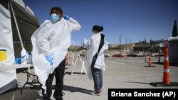 Seorang petugas mengenakan alat pelindung diri baru di fasilitas lantatur tes Covid-19 di El Paso, Texas, 26 Oktober 2020. (Briana Sanchez/The El Paso Times via AP)