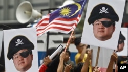 FILE - Protesters hold portraits of Jho Low illustrated as a pirate during a protest in Kuala Lumpur, Malaysia, April 14, 2018.