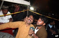 A man comforts a family member of a factory worker buried in rubbles after the building collapsed in Lahore, Pakistan, Wednesday, Nov. 4, 2015.
