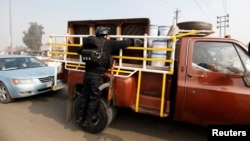 A police officer searches a vehicle at a checkpoint as security increases after a bomb attack, at Abu Ghraib district in west of Baghdad, Jan. 9, 2014.