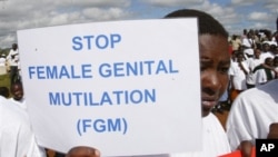 Uma menina ergue um cartaz que diz "Parem com a mutilação feminina"
