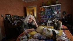 Phyllis Marder poses with her cat, Nellie, with food she recently obtained from a local food bank in the dining room of her home in Evanston, Ill. (AP Photo/Charles Rex Arbogast)