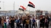 帮助政府军抗击“伊拉克和黎凡特伊斯兰国”的什叶派志愿者手持武器，高举国旗，游行走过巴格达东部的街道。（2014年6月15日）