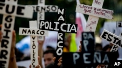 Demonstran membawa salib bertuliskan "Polisi Narkoba" dalam protes yang menuntut ditemukannya 43 mahasiswa yang diculik, di Guerrero, Mexico City (5/11). (AP/Eduardo Verdugo)