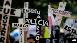 FILE - Demonstrators march with crosses with writing that reads in Spanish "Narco Cops" in protest for the disappearance of 43 students in the state of Guerrero, in Mexico City, Nov. 5, 2014.