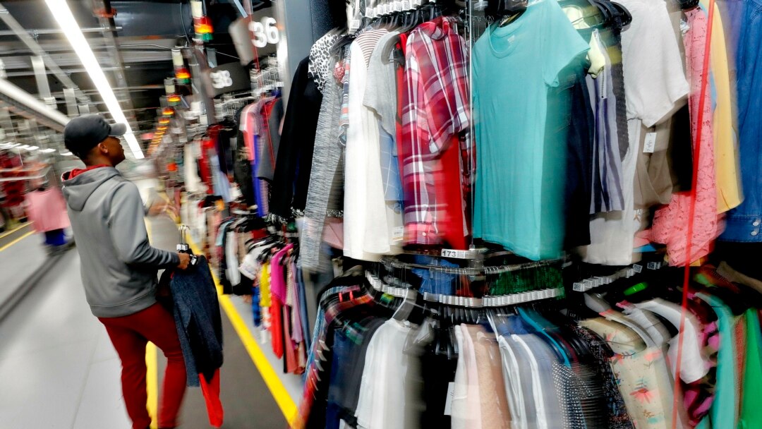Willie Walton hangs clothing on a three-level system at the ThredUp sorting center in Phoenix on March 12, 2019. Many Americans are dry cleaning their clothes again as they go back to work after being vaccinated. (AP Photo/Matt York, File)