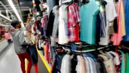 Willie Walton hangs clothing on a three-level system at the ThredUp sorting center in Phoenix on March 12, 2019. Many Americans are dry cleaning their clothes again as they go back to work after being vaccinated. (AP Photo/Matt York, File)