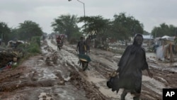 Des Sud-Soudanais se fraient un chemin dans la boue, sous une pluie battante, fuyant de violentes combats, à Malakal, au Soudan du Sud, 28 Juillet 2014. (AP Photo / Matthew Abbott)