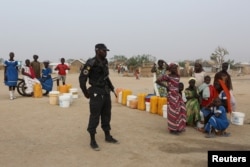 FILE - A Cameroonian police officer enforces order in Minawao, Cameroon, March 15, 2016.