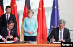 허리펑(왼쪽) 중국 국가발전개혁위원회 주임과 조 캐저(오른쪽) 독일 지멘스 최고경영자(CEO)가 5일 베를린 총리 집무실에서 양국 정상들이 지켜보는 가운데 협력사업 합의문에 서명하고 있다.