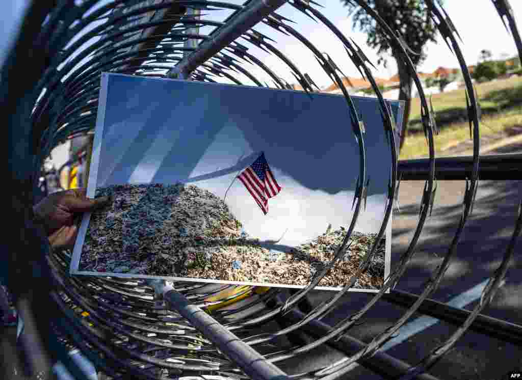 An Indonesian protester displays a picture showing the US flag on top of a trash dump during a rally in front of US consulate general office in Surabaya, in East Java, demanding the US to stop exporting waste to Indonesia.