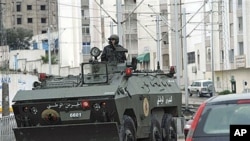 A soldier drives an armored vehicle through Ettadhamoun, west of Tunis, where riots reportedly took place, Jan 12, 2011