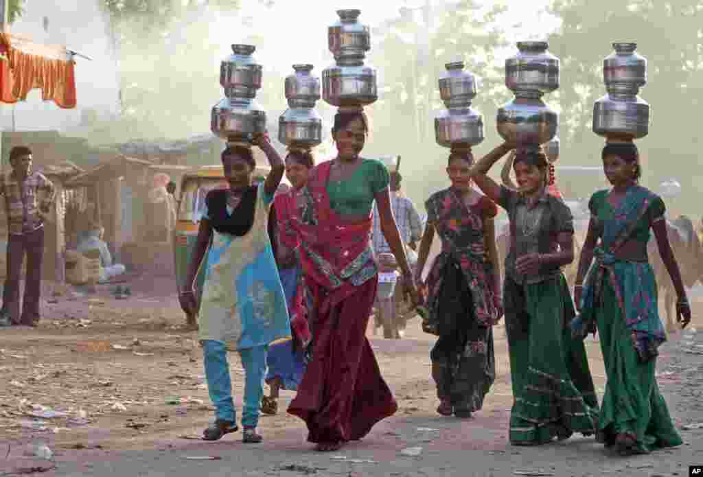 Gadis-gadis desa India membawa air dalam kendi di atas kepala mereka di desa Juval, sekitar 40 kilometer dari Ahmedabad, India.