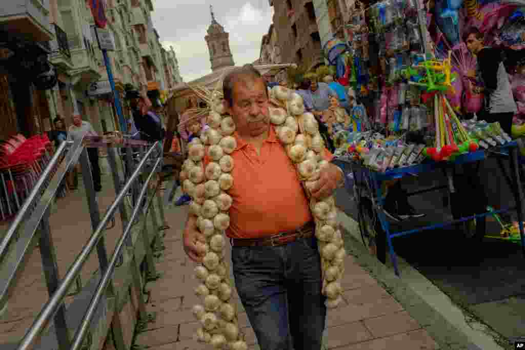 스페인 북부 비토리아의 한 시장에서 남성이 마늘 꾸러미를 매고 있다.