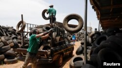 Workers offload used car tires from a truck in preparation for recycling at the Freetown waste management recycle factory in Ibadan, Nigeria Sept. 17, 2021.
