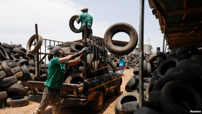 Workers offload used car tires from a truck in preparation for recycling at the Freetown waste management recycle factory in Ibadan, Nigeria Sept. 17, 2021.