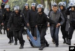 Un manifestant interpelé par la police anti-émeute, vendredi, à Tunis