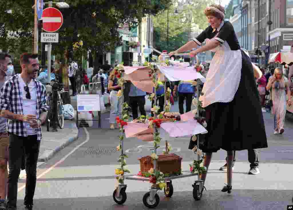 A performer on stilts interacts with a member of the public during the annual Bermondsey Street Festival in London, Sept. 19, 2020.