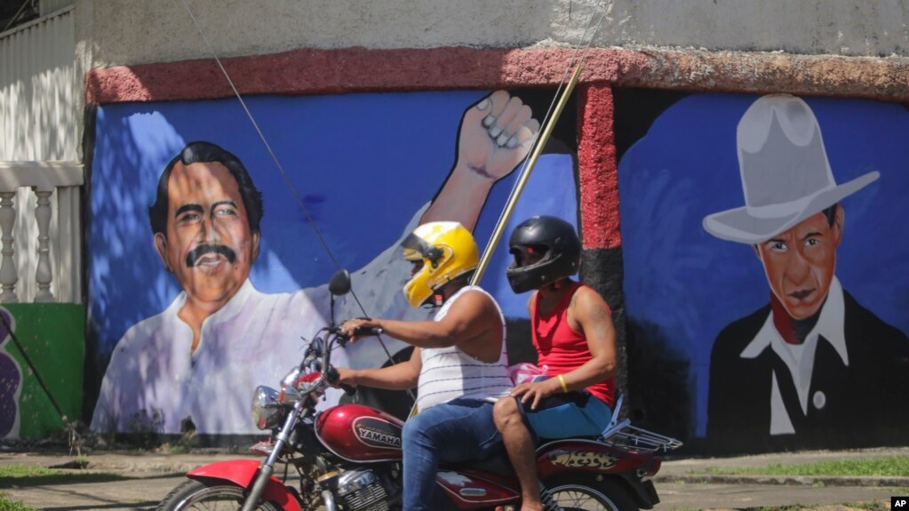 FILE - A motorcyclist rides past a mural of Nicaraguan President Daniel Ortega, left, and revolutionary hero Cesar Augusto Sandino during general elections in Managua, Nicaragua, Nov. 7, 2021. 