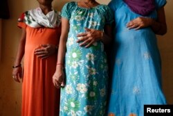 FILE - Surrogate mothers (L-R) Daksha, 37, Renuka, 23, and Rajia, 39, pose for a photograph inside a temporary home for surrogates provided by Akanksha IVF centre in Anand town, about 70 km (44 miles) south of the western Indian city of Ahmedabad, Aug. 27, 2013.