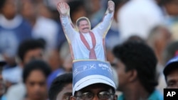 A supporter sports a cut-out of Sri Lankan President Mahinda Rajapaksa on his head, during Rajapaksa’s final public rally for the presidential elections in Kesbewa, about 20 kilometers (12 miles) southeast of Colombo, Sri Lanka, Monday, Jan. 5, 2015.