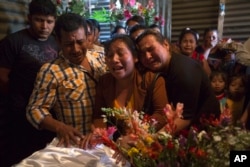 Marta Lidia Garcia, center, cries during the wake of her 17-year-old daughter Siona Hernandez, who died in a youth shelter fire, in Ciudad Peronia, Guatemala, March 10, 2017.