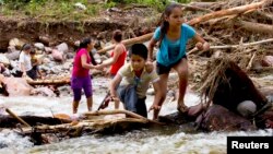 Dos niños cruzan una quebrada en las montañas de Zihuatanejo, estado de Guerrero, luego del paso del huracán "Manuel".