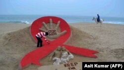 Seniman India, Sudersan Pattnaik, merapikan pahatan pasir pada malam peringatan Hari AIDS Sedunia di Pantai Laut Emas, di Puri, India, 29 November 2013. (Foto: AFP/Asit Kumar)