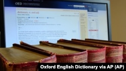 This undated image released by the Oxford English Dictionary (OED) shows old volumes of the dictionary next to a computer monitor displaying a page from the OED website. The OED has added about 1,000 new entries.